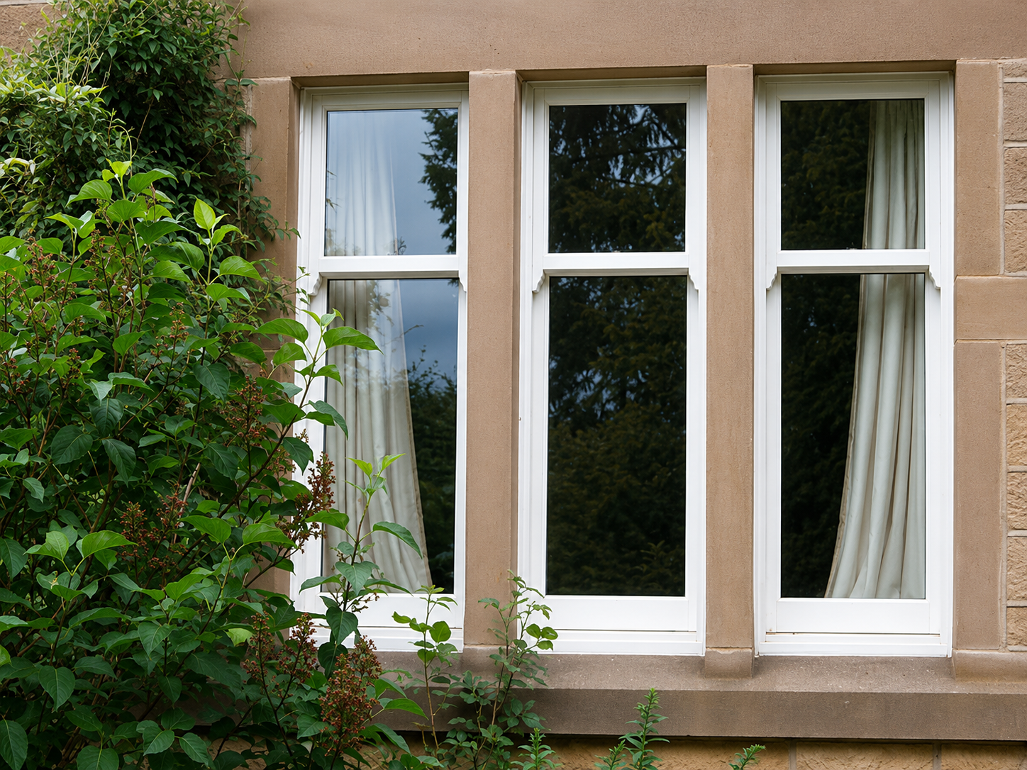 White PVCu sliding sash windows on a period stone property