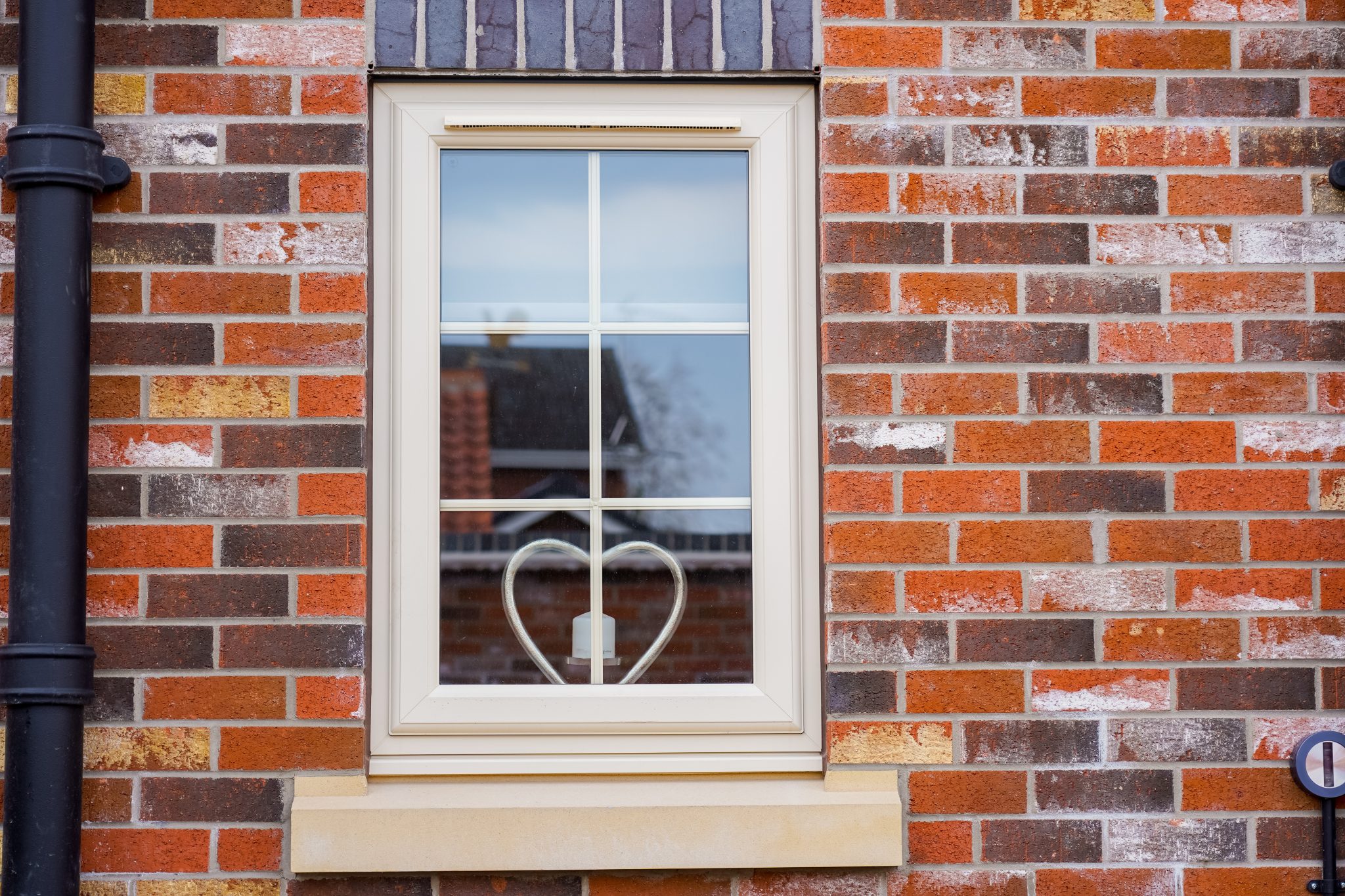 Cream PVCu casement window with Georgian bars installed on a modern brick home