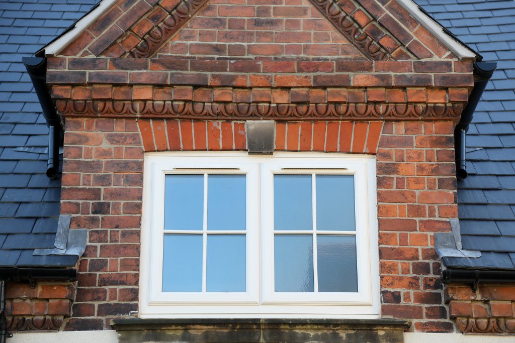 White PVCu casement windows with Georgian bars installed in a traditional brick home