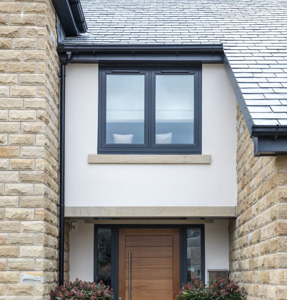 Anthracite grey flush fit PVCu windows and timber entrance door fitted on a stone built home in Derbyshire