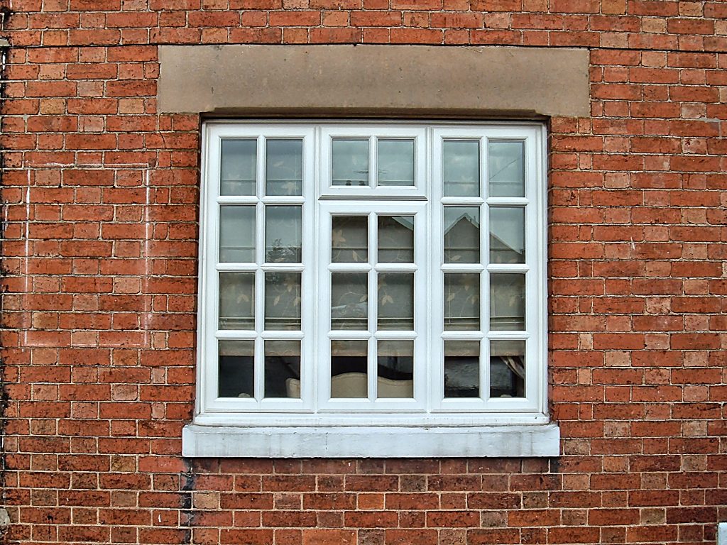 White hardwood casement window with Georgian bars in a red brick wall, Derby