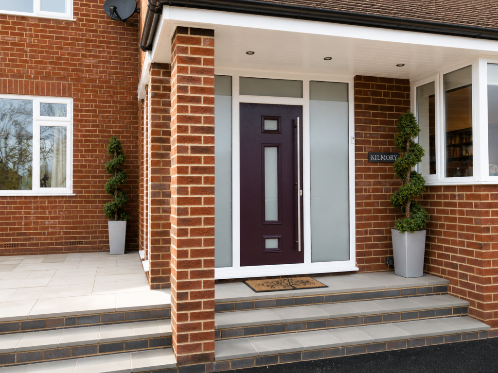Plum composite front door with frosted glazed panels and matching side lights, finished with a long stainless steel pull handle, set within a modern brick porch entrance.