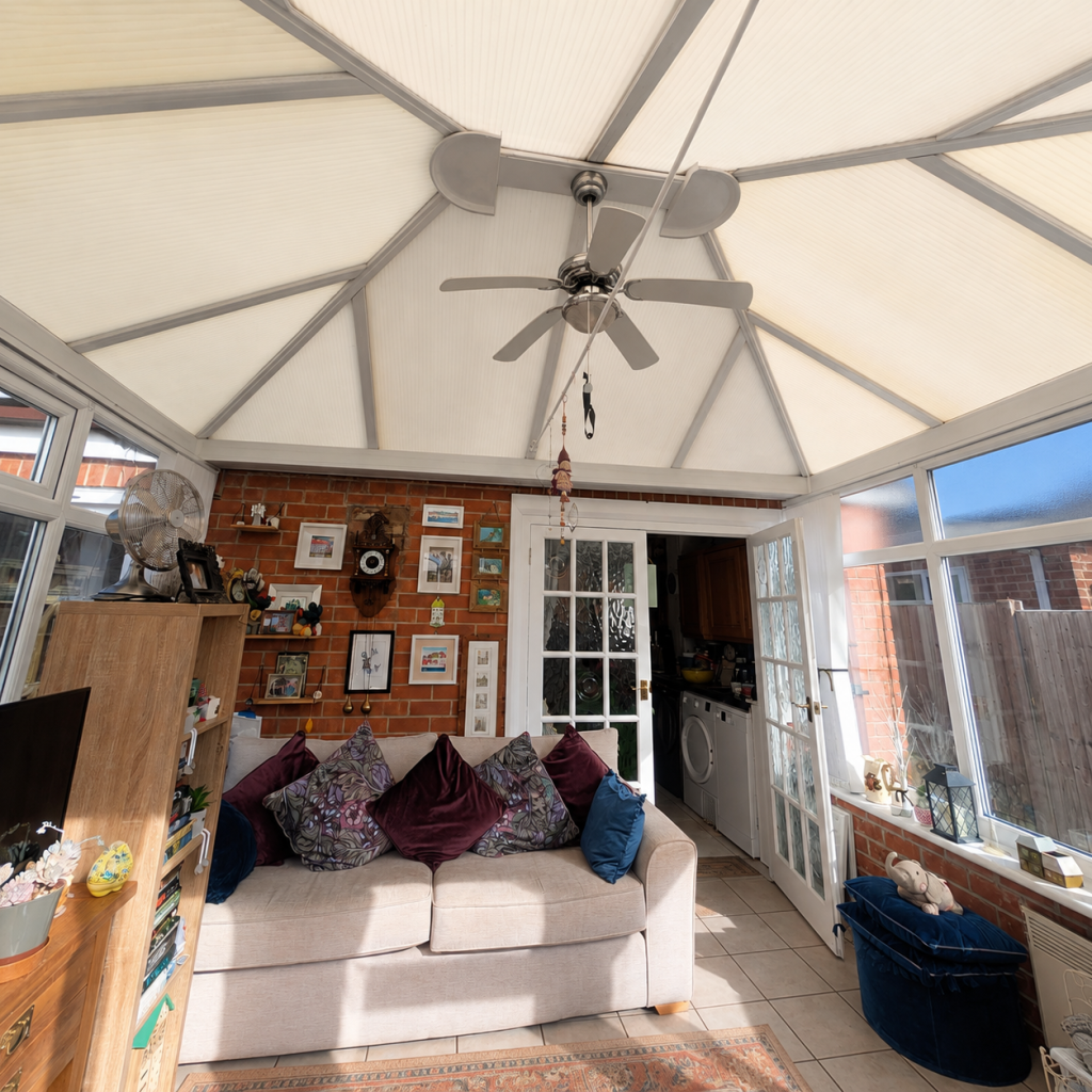 Old conservatory roof with yellow-stained polycarbonate panels and dated white roof framework.